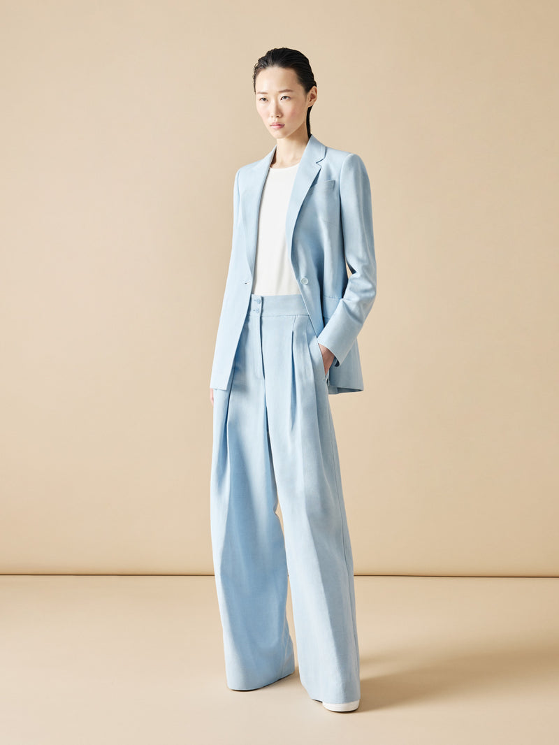 Asiatisches Model trägt einen hellblauen Hosenanzug mit weissem T-Shirt von Akris punto.