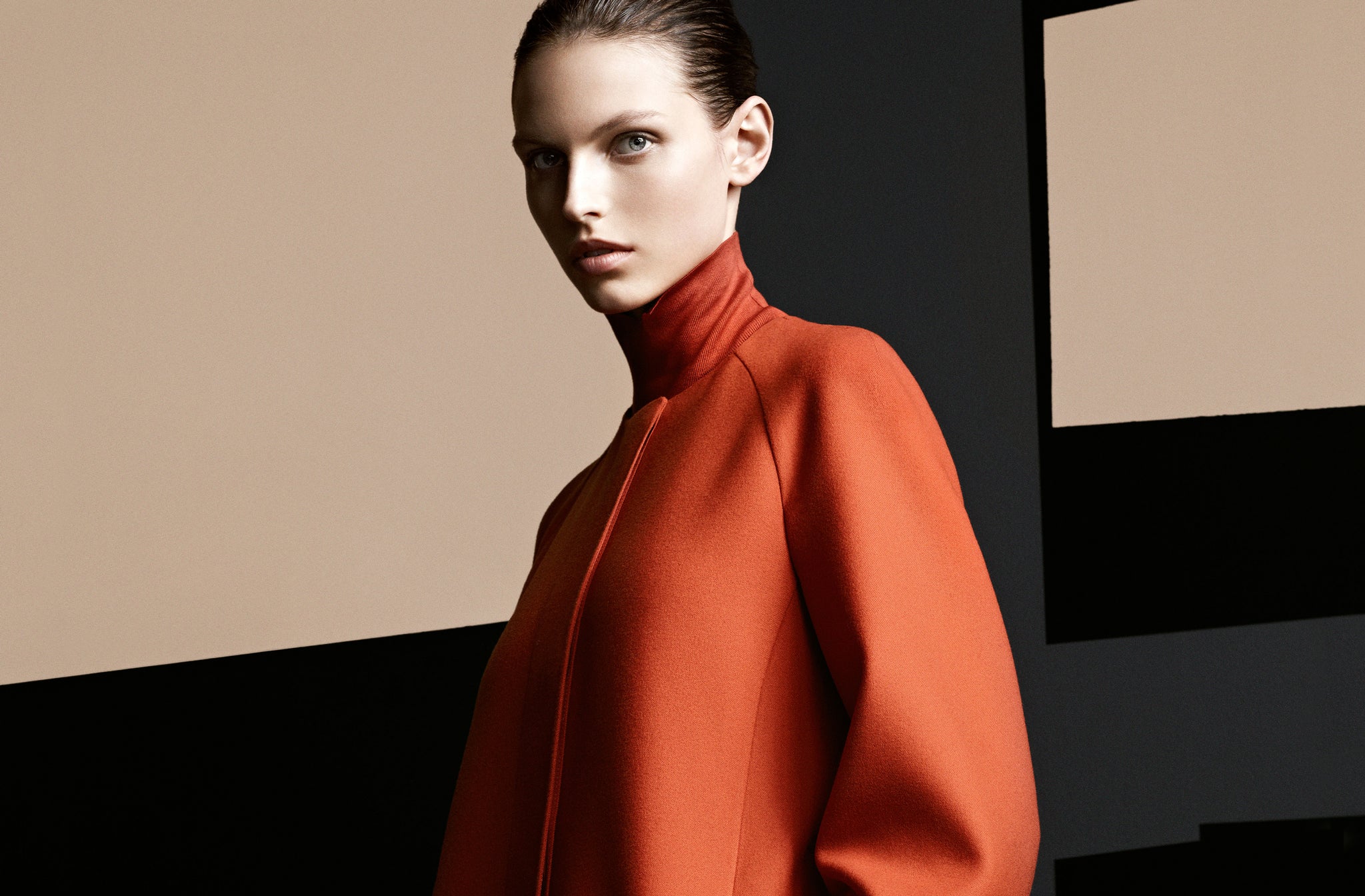 Dame in einem orange-roten Mantel und passendem Rollkragenpullover dazu.