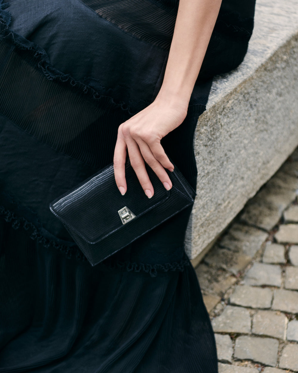 Schwarze Clutch Tasche von Akris in der Hand von einer Dame.